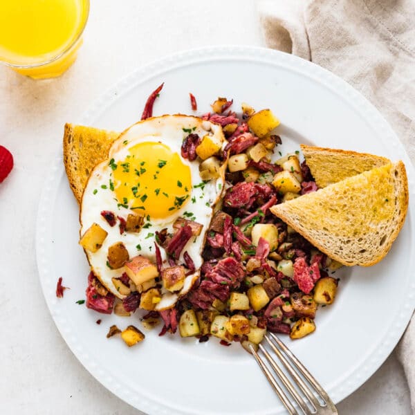 corned beef hash with eggs and toast on a plate.