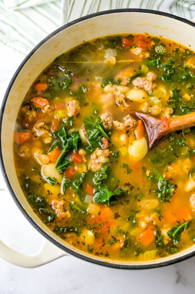 a dutch oven full of Italian sausage kale and white bean soup.