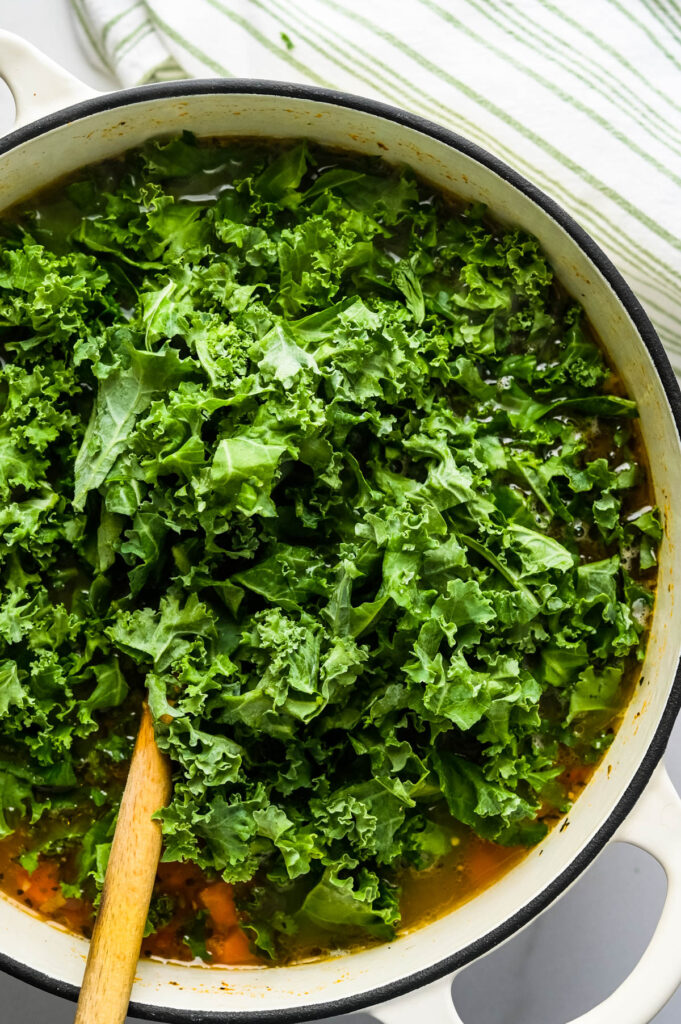adding chopped kale to the pot.