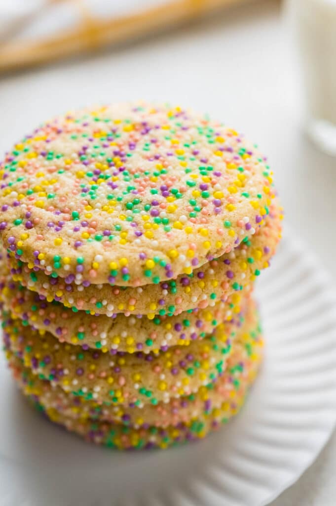 A stack of chewy lemon sprinkle cookies on a plate with pastel colored nonpareils.