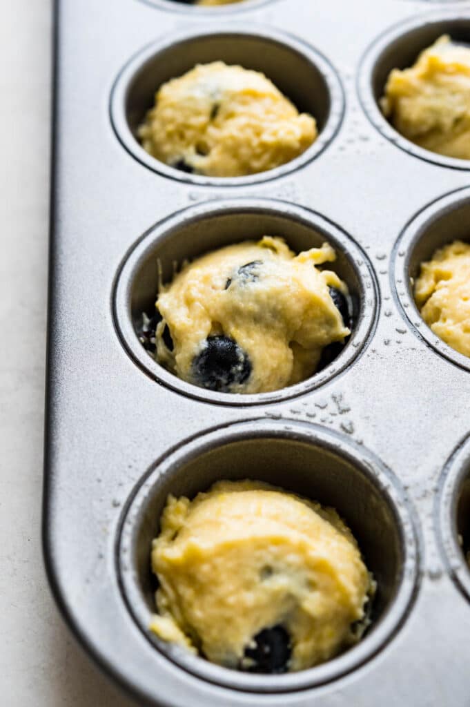 portioning out the blueberry muffin batter into mini muffin tins.