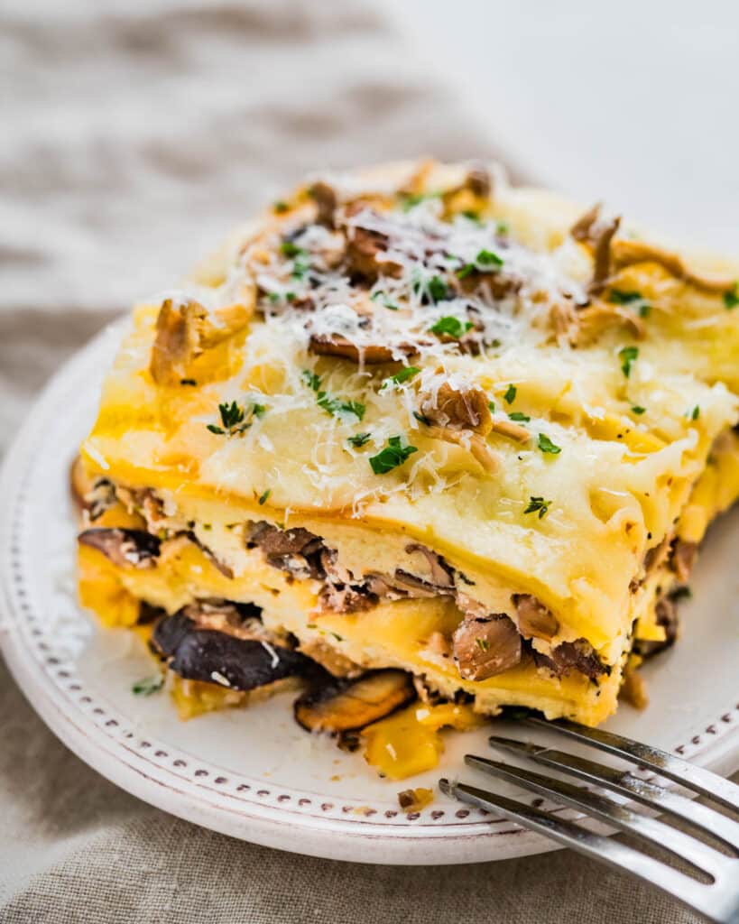A slice of mushroom lasagna with a fork on a plate.