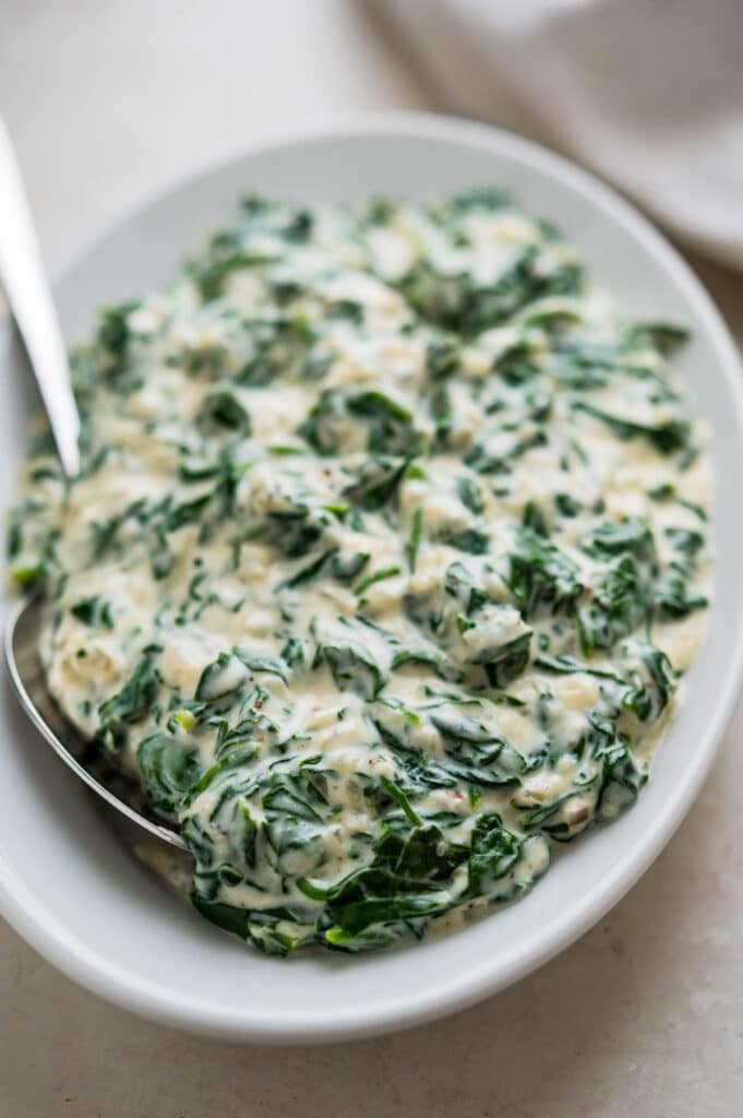 serving the creamed spinach on a plate.