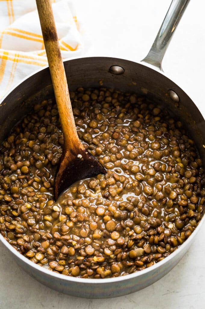 cooked brown lentils in a pot after seasoning.
