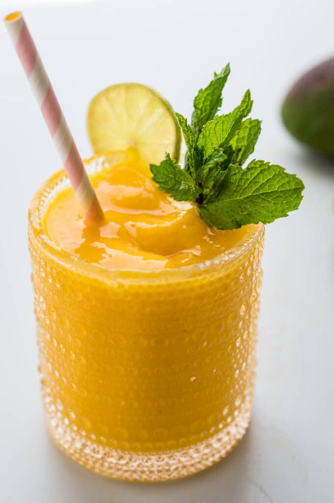 frozen mango daiquiri in a glass with mint, lime and a straw!