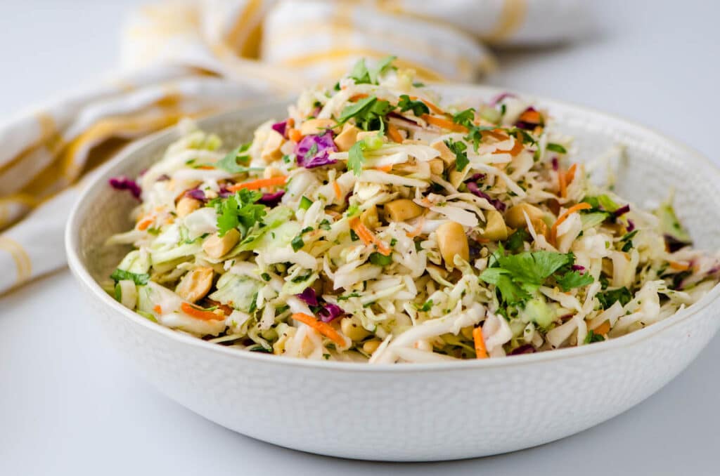 a horizontal image of the Asian slaw recipe with peanuts, cilantro, mint, jalapenos.