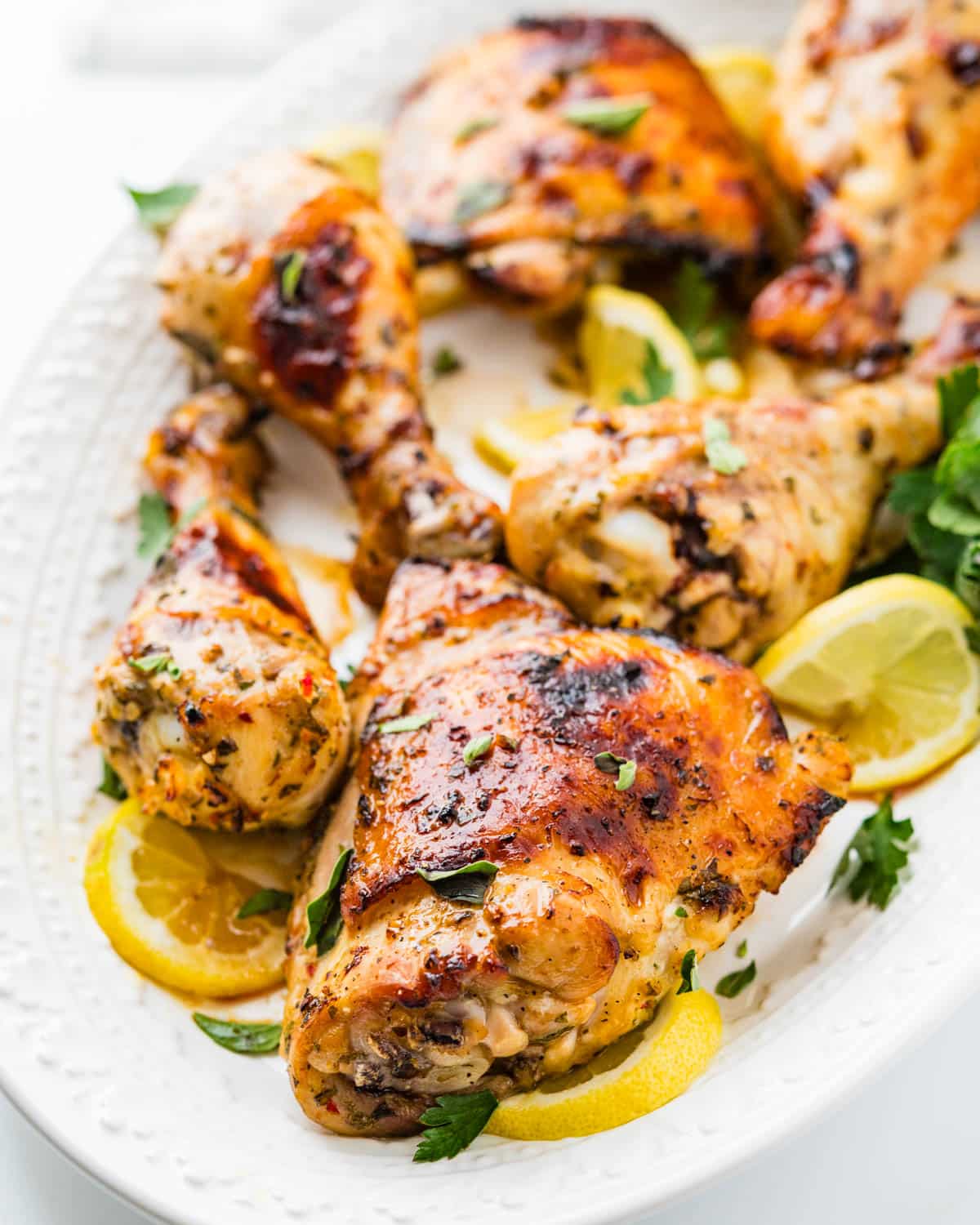 A platter of baked lemon chicken with lemon slices.