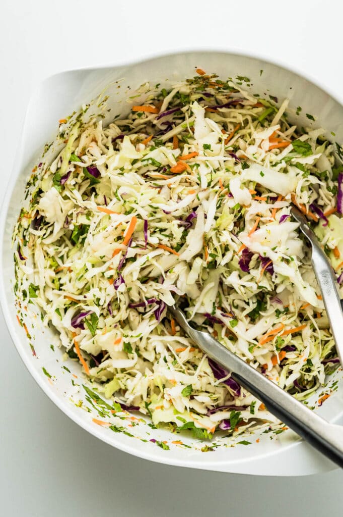 adding the slaw and cilantro to the easy lime dressing.
