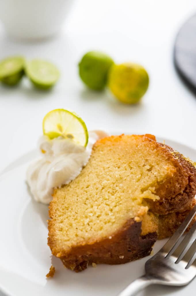serving key lime cake with a scoop of whipped cream and a slice of key lime.