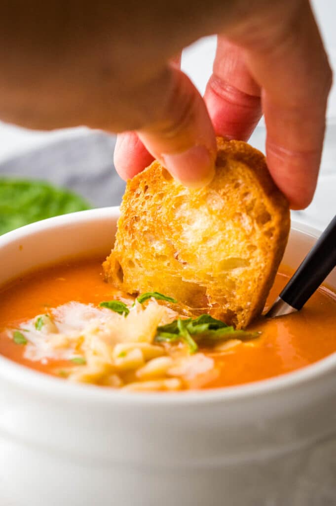 Dipping a crouton into the cream of tomato soup.