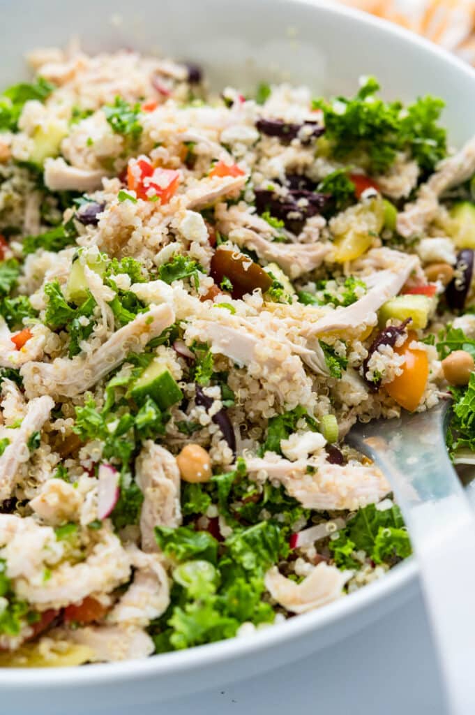 tossing the Mediterranean Chicken Quinoa salad with the dressing.