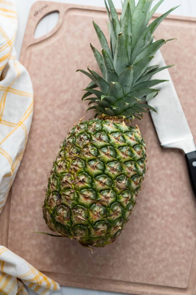 a pineapple on an Elihome board with a knife.