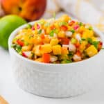 serving peach salsa in a white bowl.