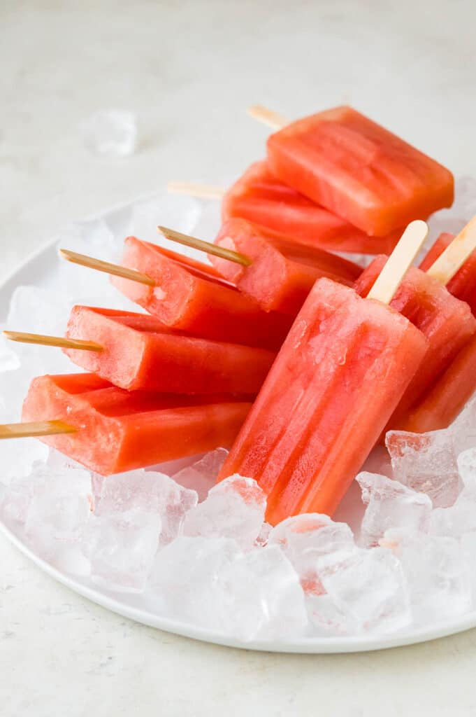 A stack of watermelon popsicles on a bed of ice. 