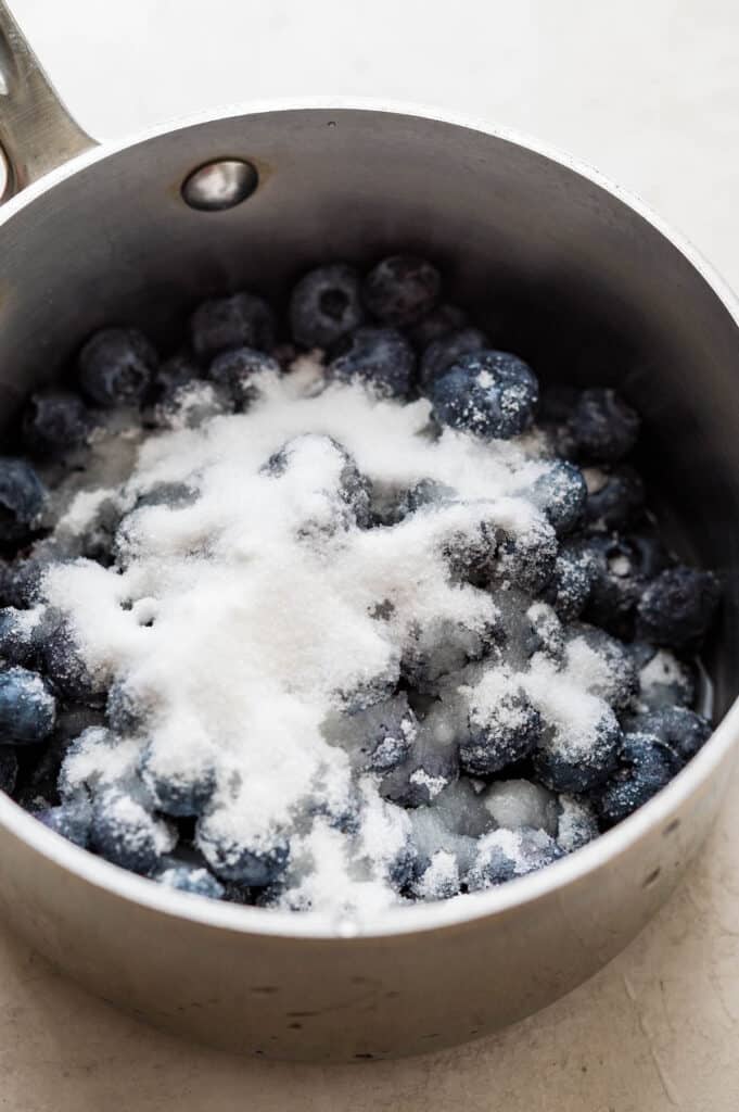 Adding blueberries and sugar to a non reactive pan.