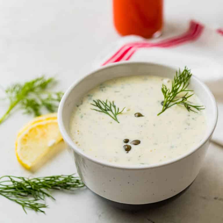 tartar sauce in a serving bowl with extra dill, capers and lemon.