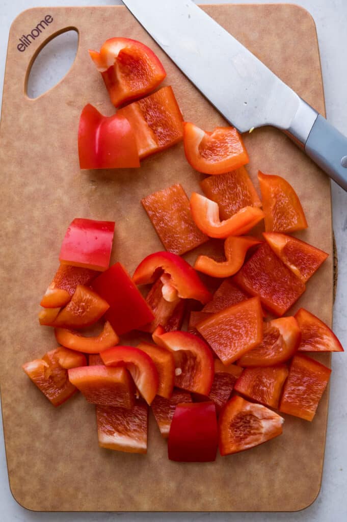 chopping red bell pepper on a cutting board.
