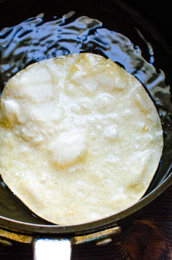 frying a corn tortilla in hot oil to make chalupas.