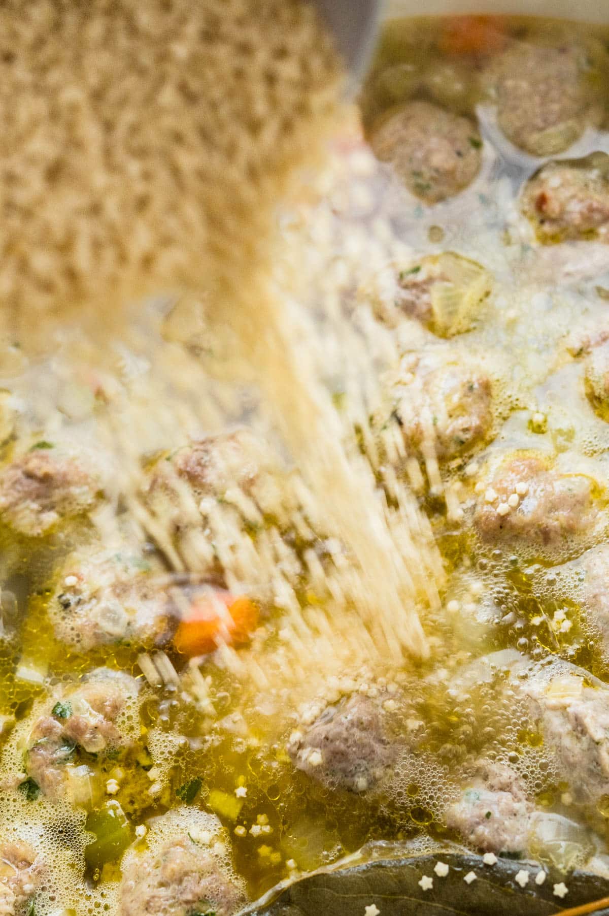 pouring pasta into Italian wedding soup recipe. 