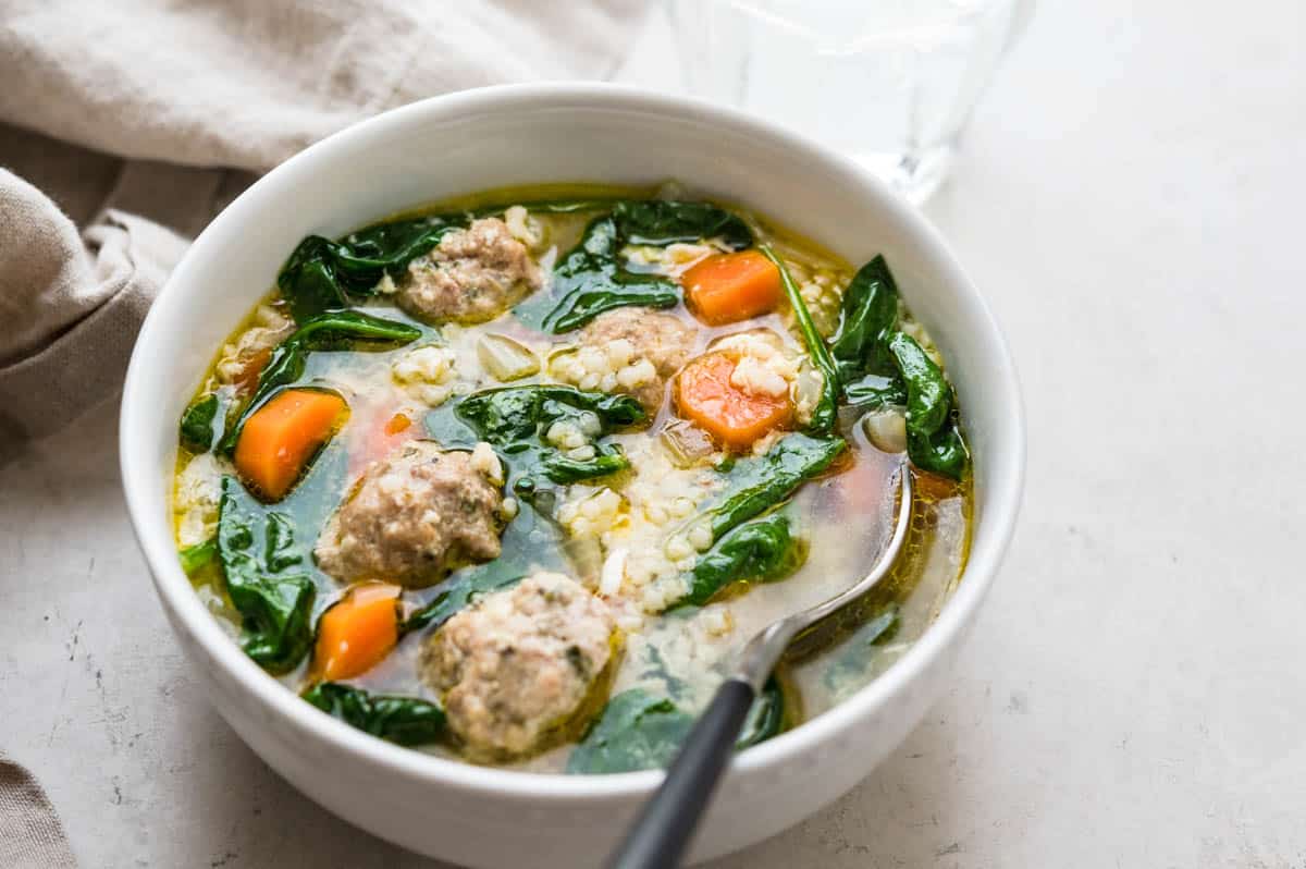 a white bowl of the wedding soup recipe with a spoon.