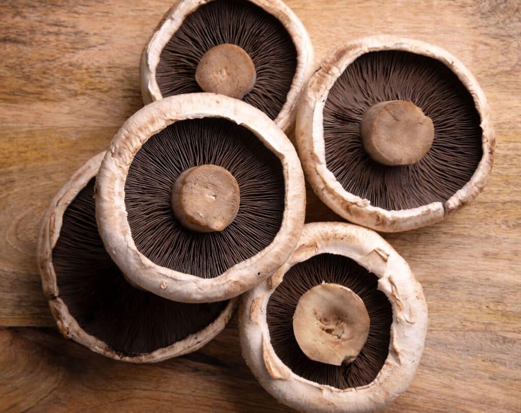Portobello mushroom caps on a cutting board.