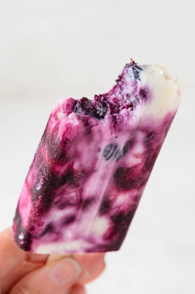 taking a bite out of the frozen blueberry yogurt popsicle.
