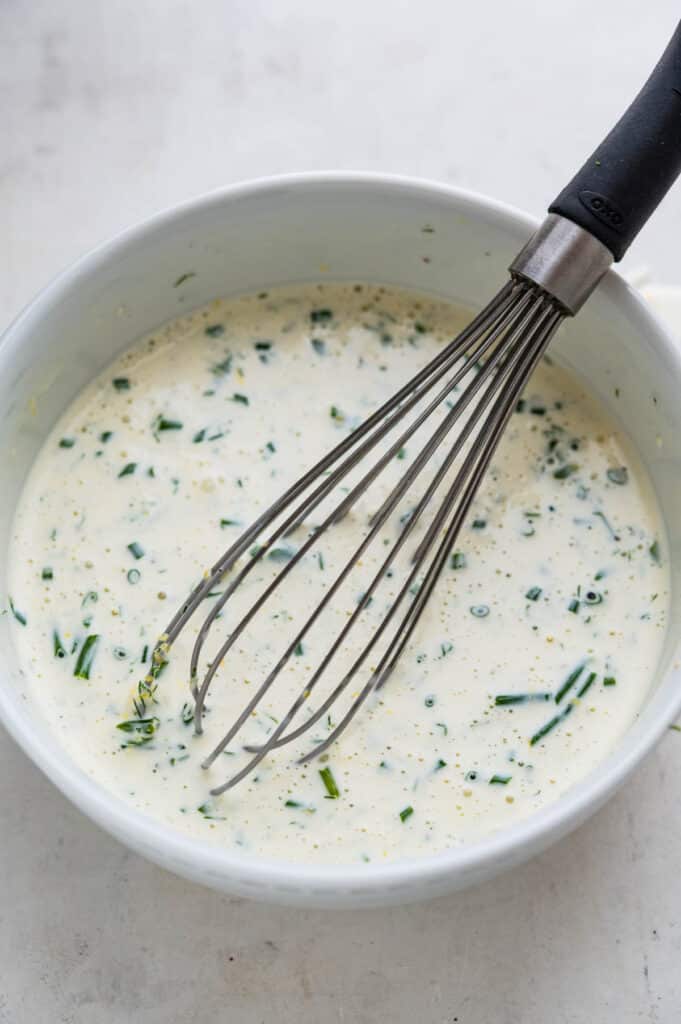 Whisking fresh herbs into the buttermilk dressing.