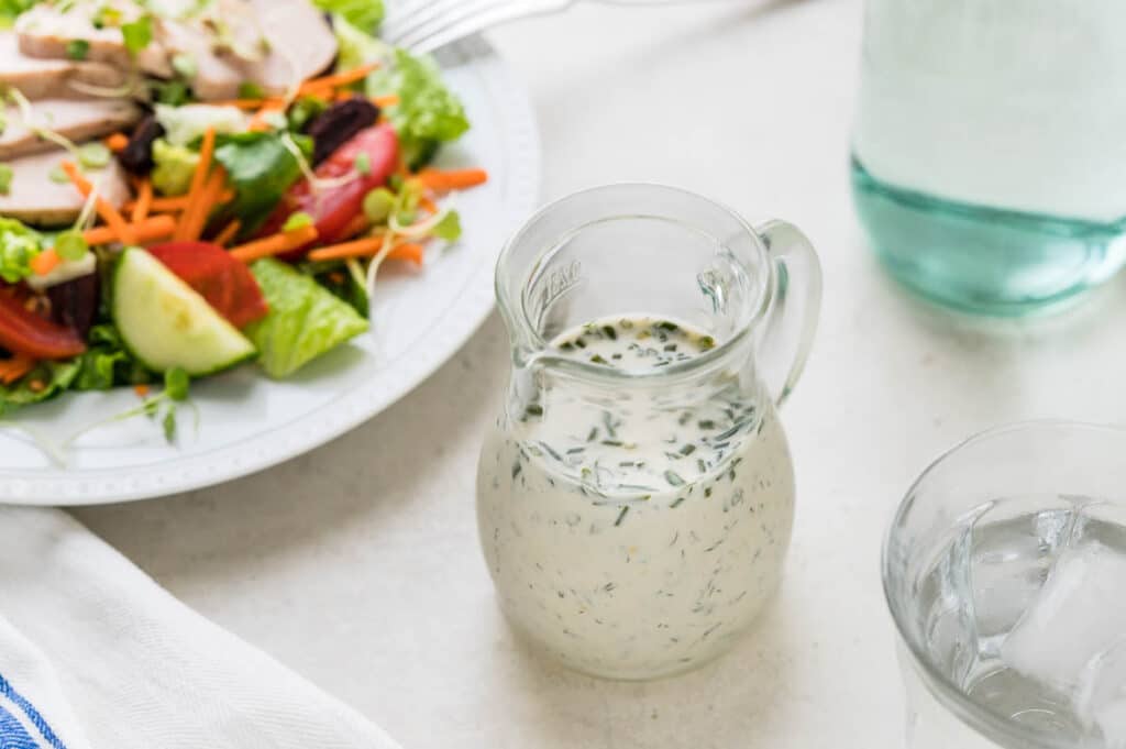Serving the homemade lemon herb buttermilk dressing with a green salad topped with sliced chicken. 