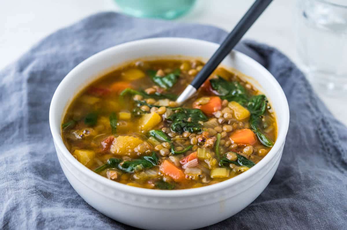 butternut squash and lentil soup in a white bowl with a spoon.