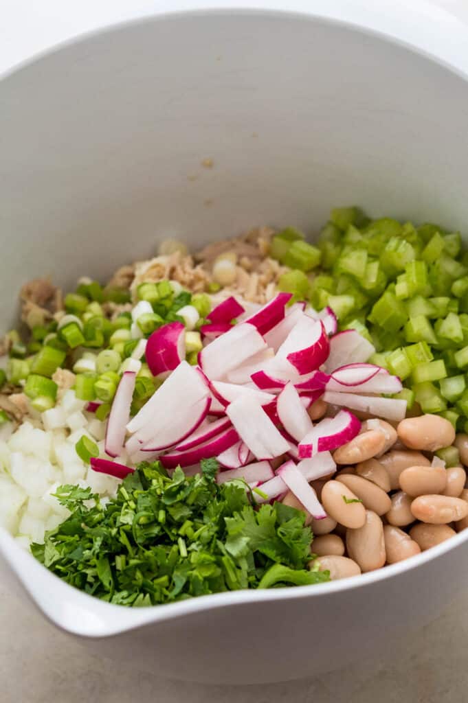 Combining the tuna white bean salad and veggies in a large mixing bowl.