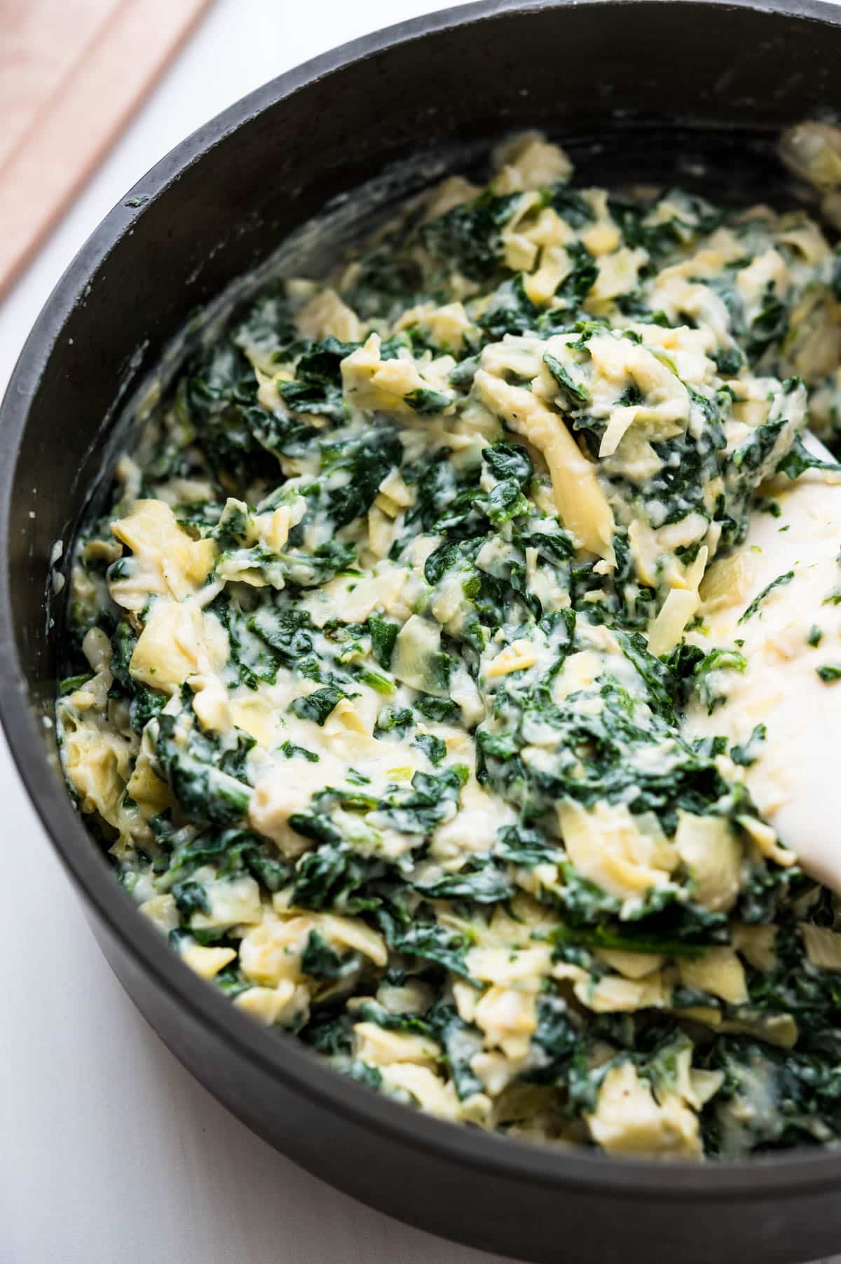 mixing the spinach artichoke dip recipe in the skillet.