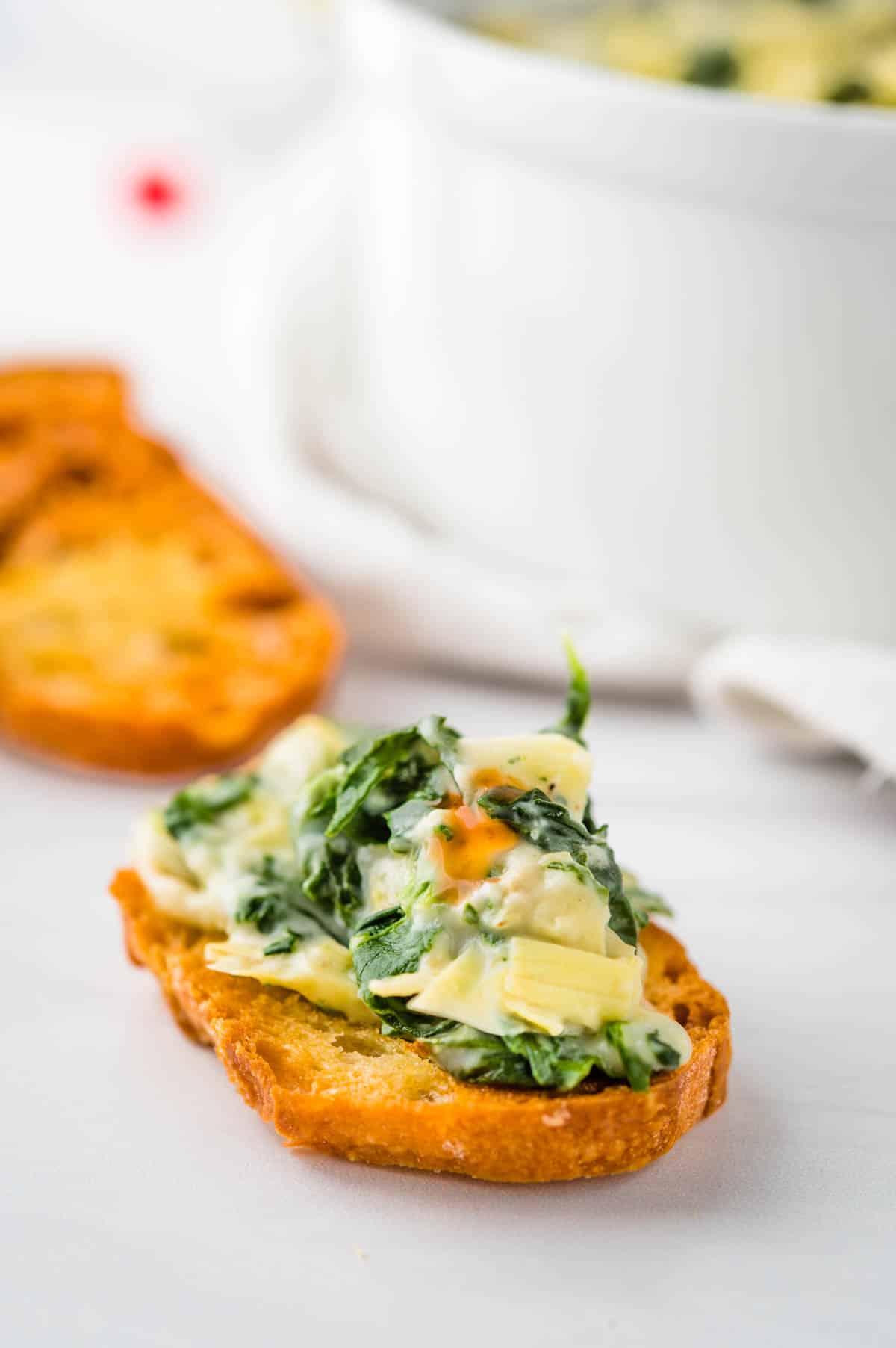 A crunchy crostini cracker topped with warm baked spinach artichoke dip.