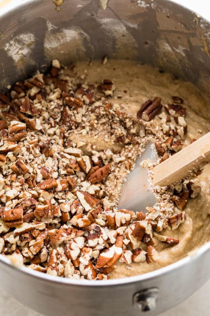 adding toasted pecans to the banana bread batter.