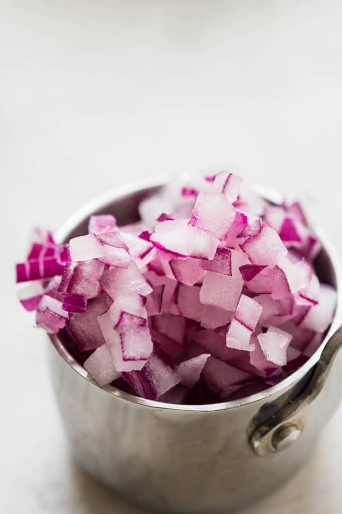 Diced red onions in a measuring cup.