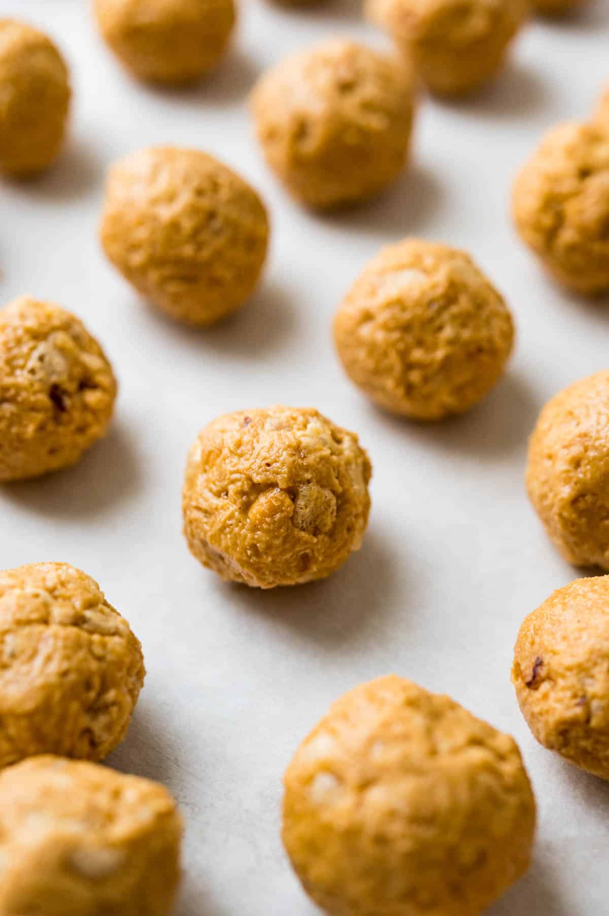 rolling rice krispie peanut butter balls and resting on a cookie sheet.