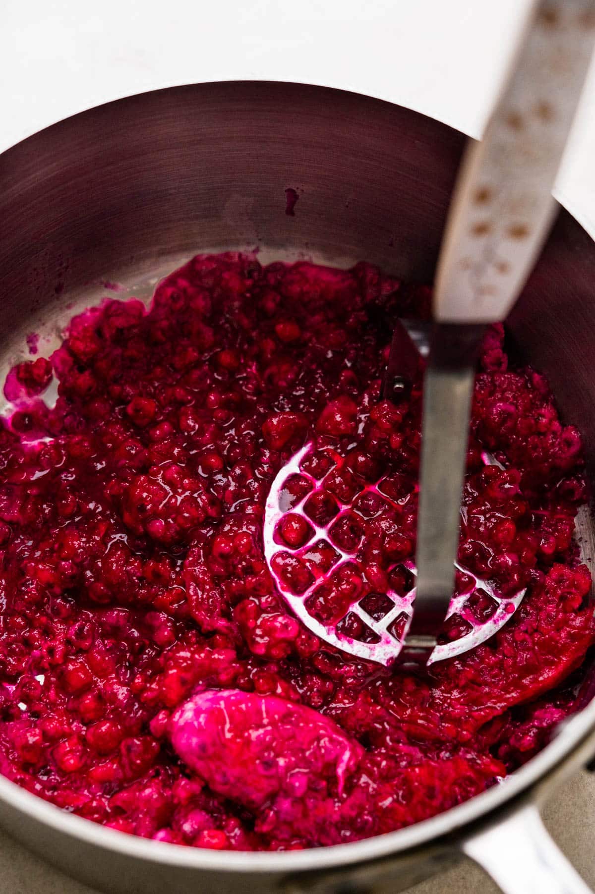 mashing prickly pear pulp with a potato masher.