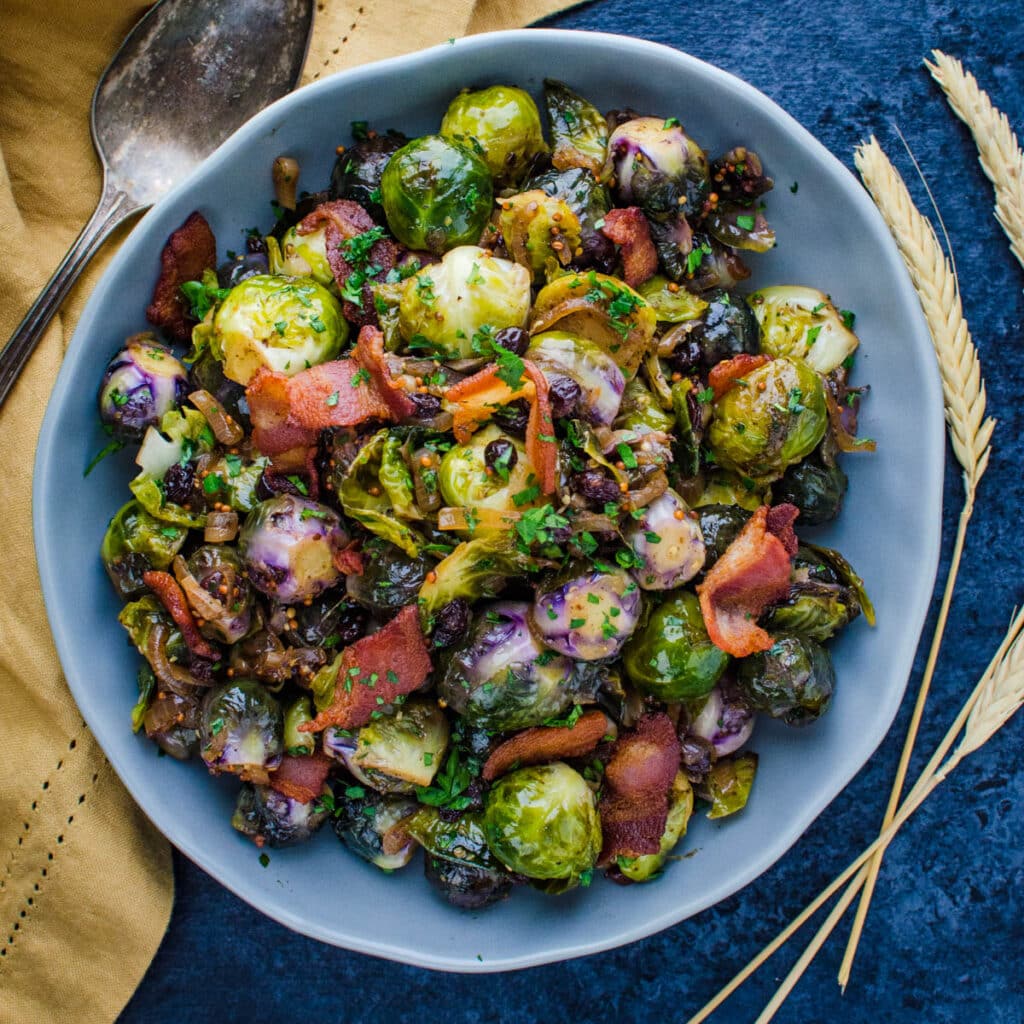 glazed brussel sprouts in a serving dish with stalks of wheat on the side.