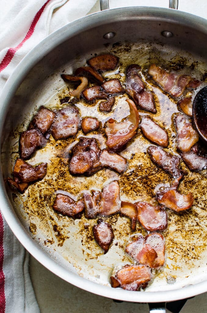 crisping bacon in a pan.