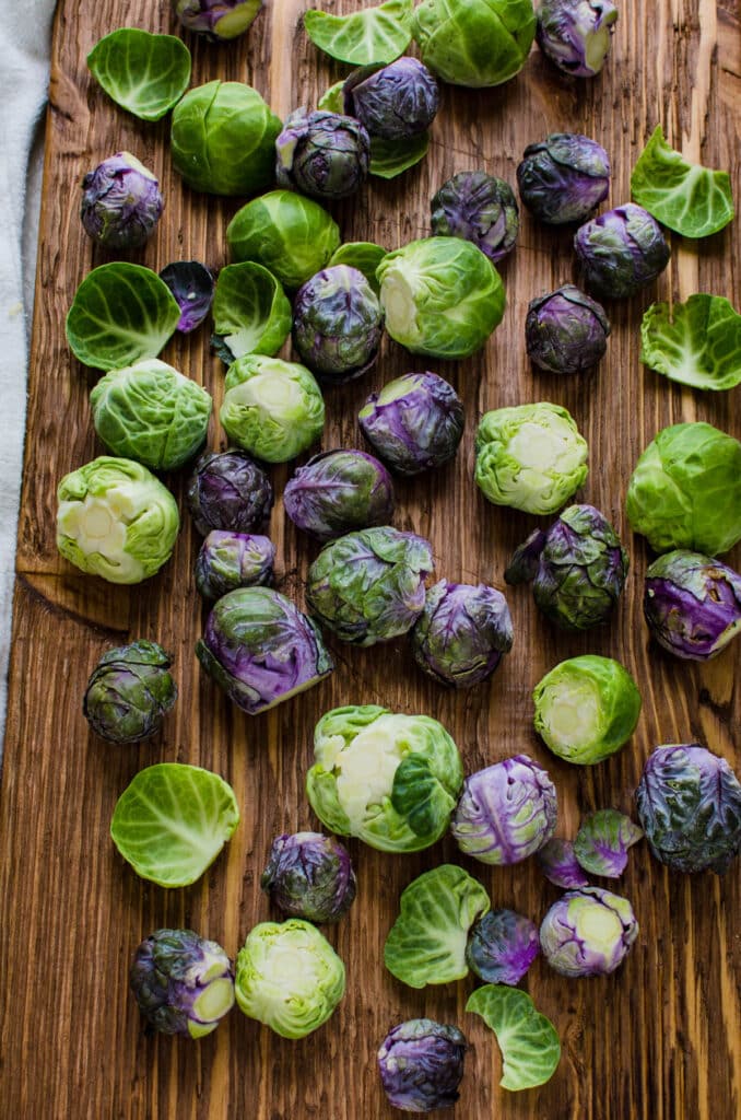 green and purple brussels sprouts on a cutting board. 