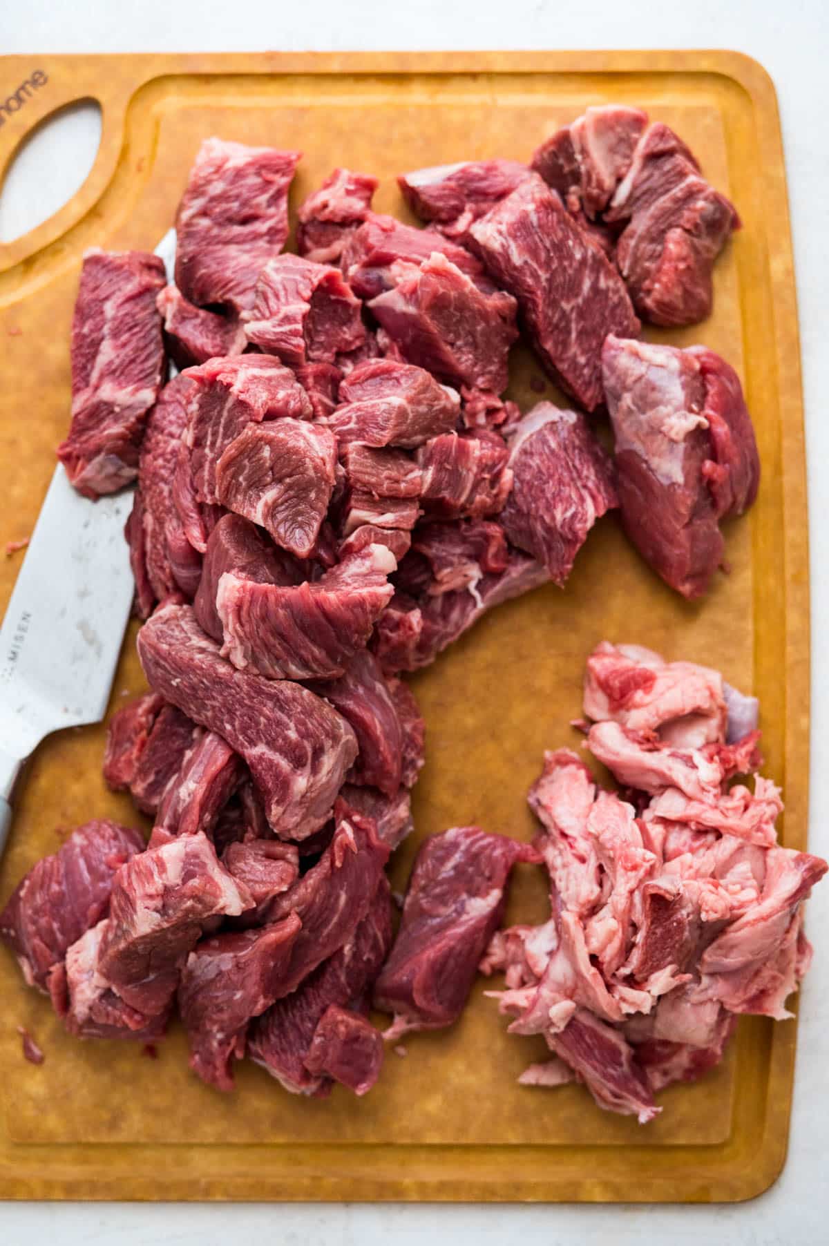 slicing beef into small strips and removing excess fat.