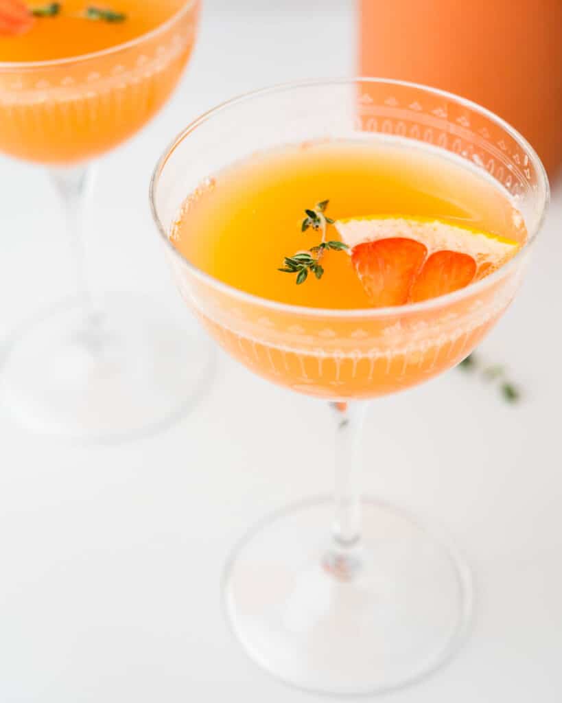 A coupe glass filled with a grapefruit mimosa.