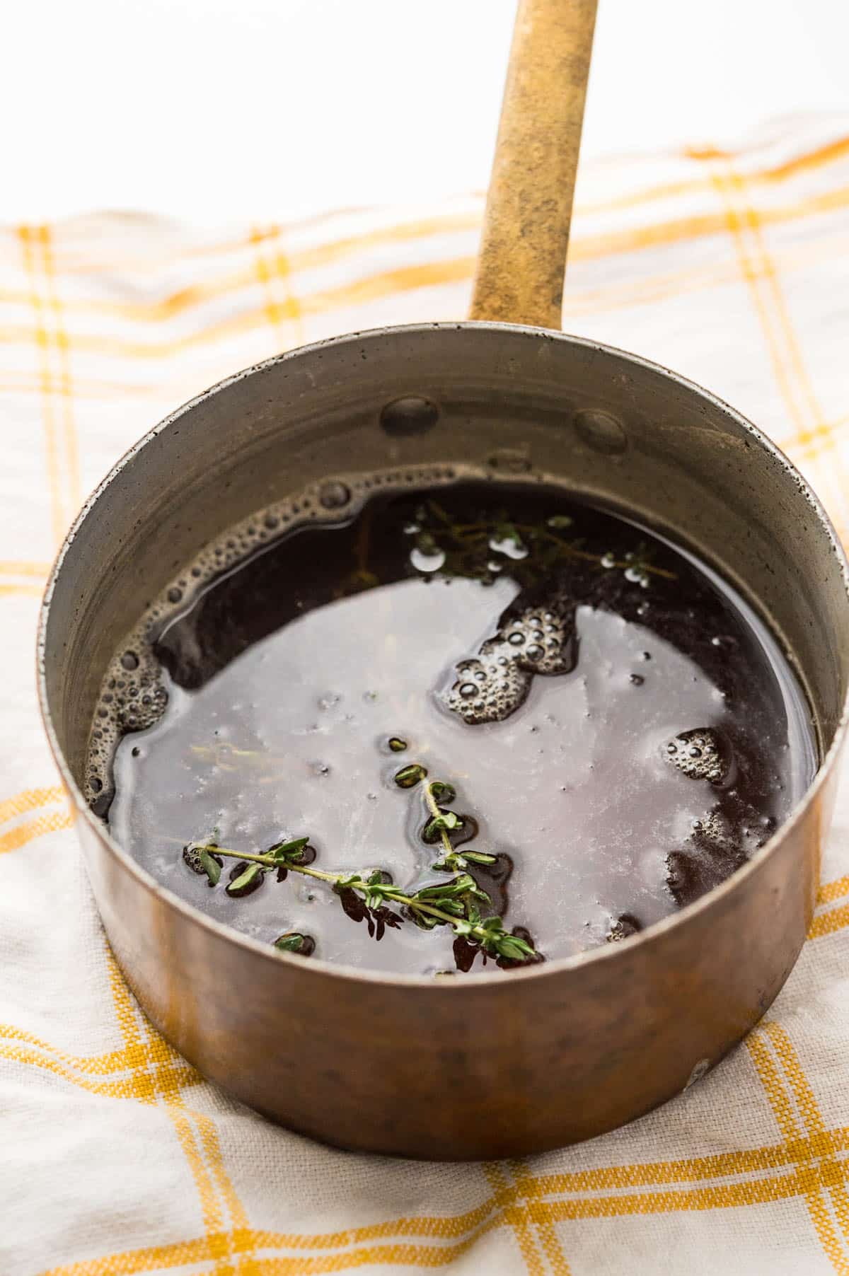 a saucepan with water, honey and thyme leaves.