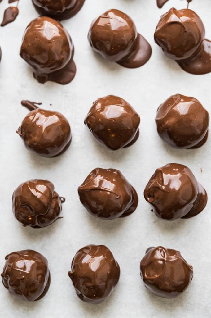 Chocolate-dipped peanut butter balls on a piece of parchment paper. 