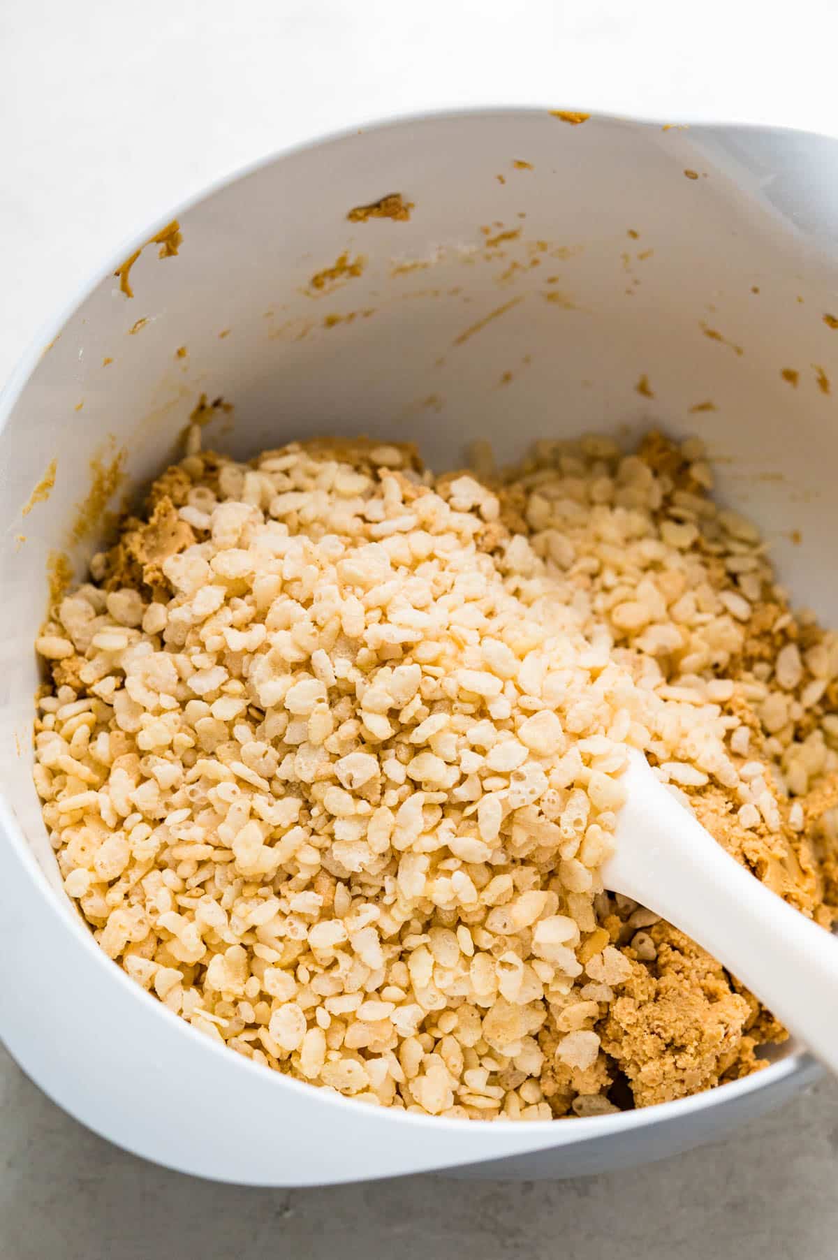 adding Rice Krispies cereal to the peanut butter mixture.