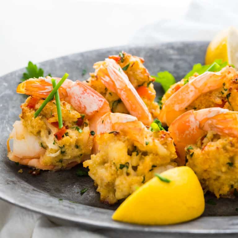baked crab stuffed shrimp on a platter with lemon wedges.