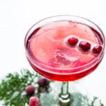 A cranberry mimosa with 3 berries floating in it.