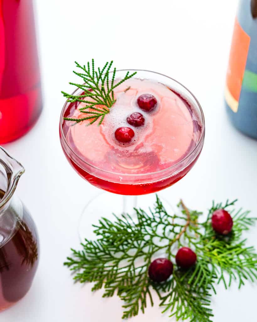 A cranberry mimosa with cranberries and greenery.