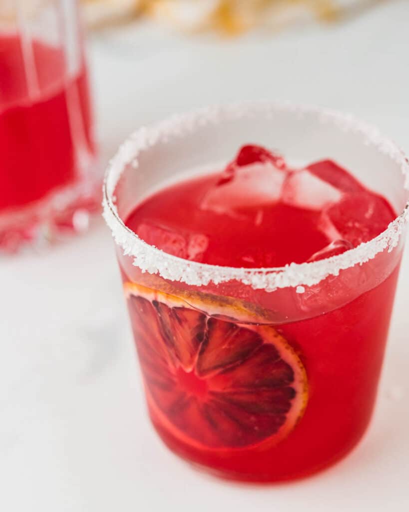 A decorative way to serve the blood orange margarita with a whole orange slice pressed to the inside of the glass.