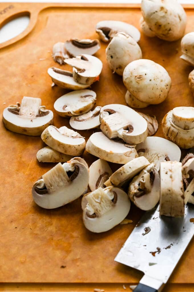Slicing button mushrooms on a cutting board. 