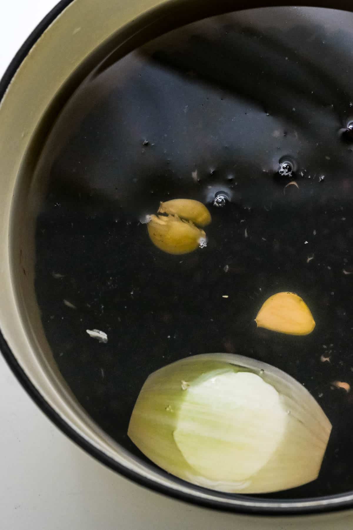 black beans garlic and onions in a pot covered with water.